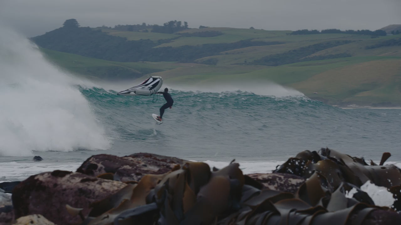 A rider wing foiling off a breaking wave